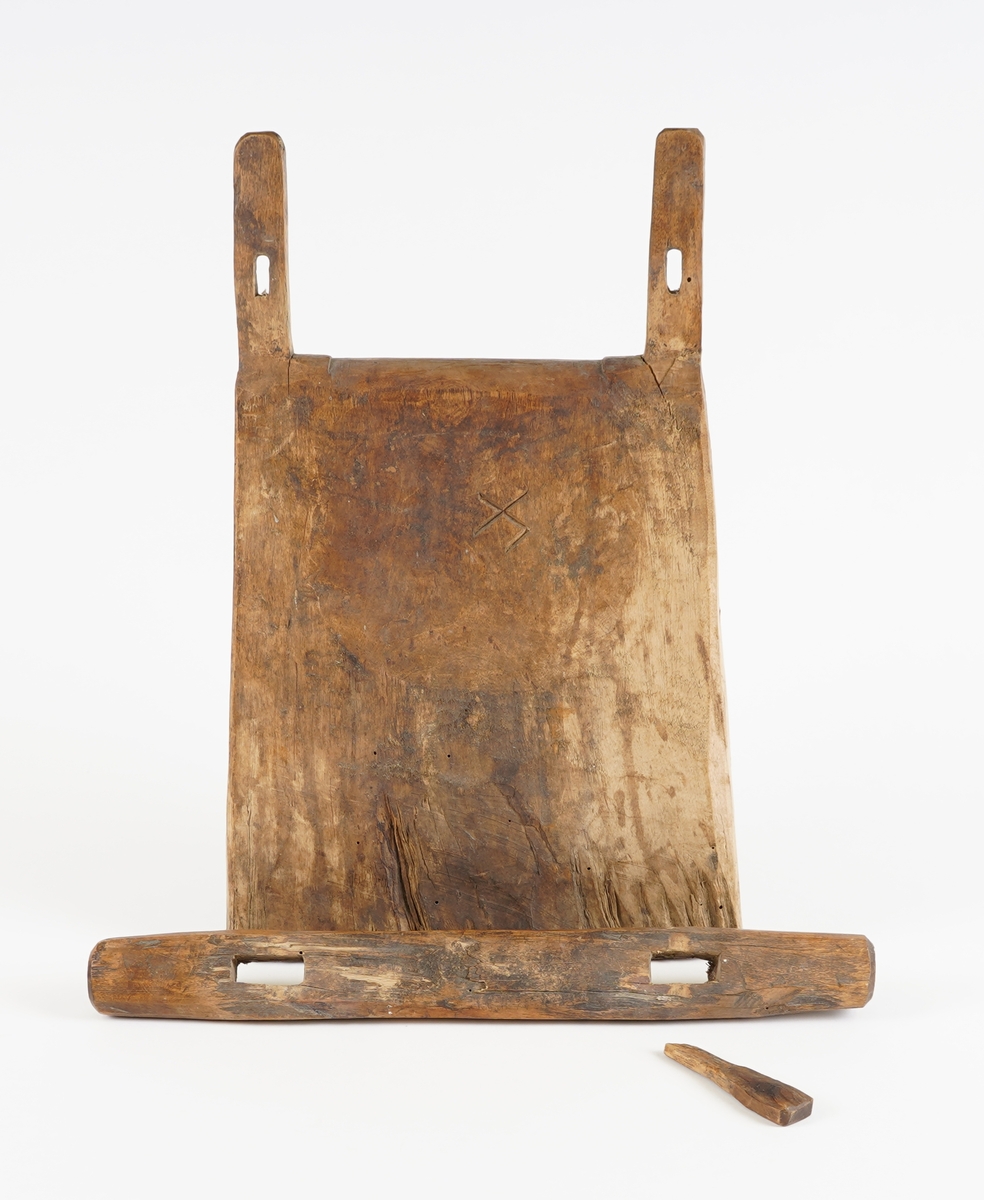 Klappestokk (til kastrering, truleg av værlam). I tre. Hovuddel som står av seg sjølv, bogar noko utover på eine breisida, innover på andre breisida. øvst endar hovuddel med to opprette pinnar med hol gjennom. Ned over pinnane er tredd ein stokk (kan fjernast). Denne er fest med ein kile i eine holet. Bumerke ein kross med ein ekstra strek.