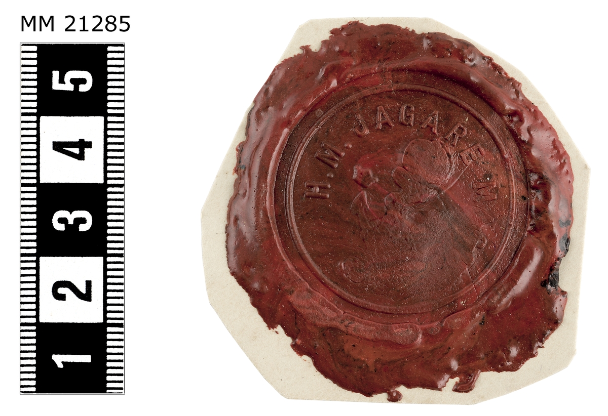 Sigillavtryck av rött lack på papper. I mitten krönt stockankare omgivet av tre kronor. Längs kanten text: "H.M. Jagare Magne".