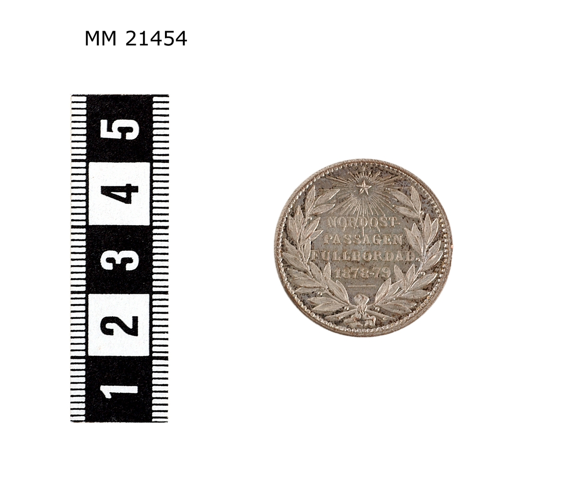 Minnespenning av silverplätering. Åtsida: Huvud i profil av man med mustasch. Under bild text : "LINDBERG". Längs kanten text: "ADOLF ERIK NORDENSKIÖLD". Prickad rand längs kanten.

Frånsida Lagerkrans runt kanten, överst strålande stjärna, text i mitten: "NORDOSTPASSAGEN FULLBORDAD 1878-79".