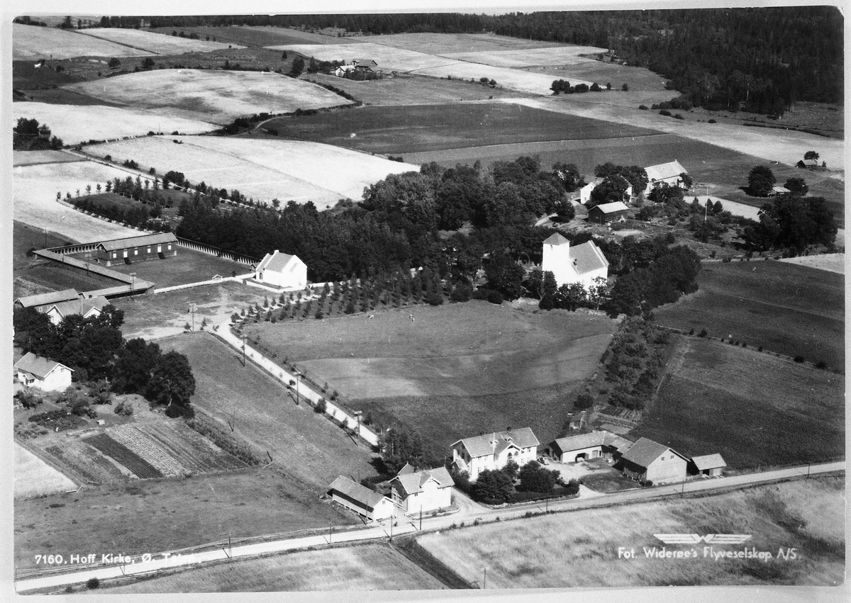 Hoffsvangen med Hoff kirke. Flyfoto tatt ca. 10 år etter at bjørkene mellom kirka og gravkappelet ble plantet.