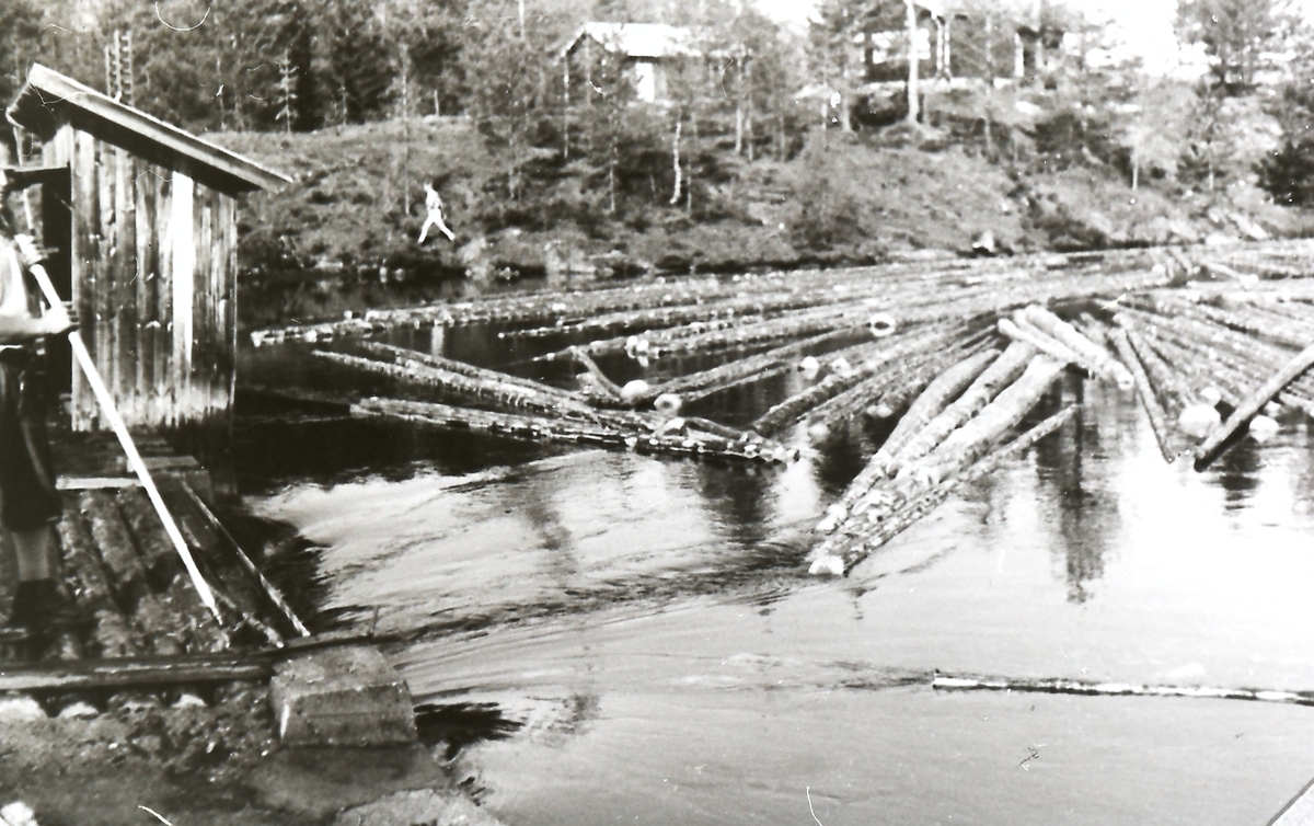 Utstikking av tømmer i sørenden av Hengsvann, Hengsvannstua i bakgrunnen. Personen til venstre er Ivar Aslaksen Lundeberg (1928-1980).