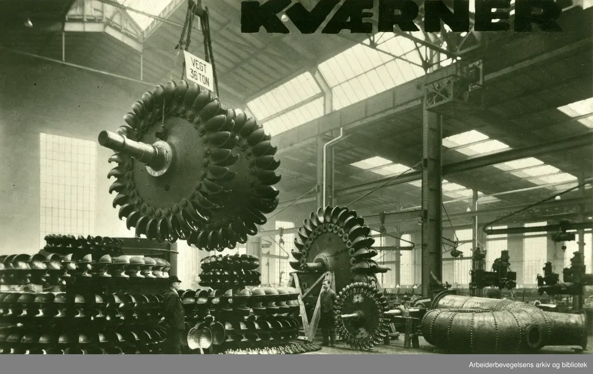 Kværner Brug. " En enestående samling peltonhjul. Interiør fra det nye opstillingsverkstedet. 14 hjul samt løse skovler som skal benyttes til 2 hjul. representerer ialt 80 000 kw." Foto ca. 1930.