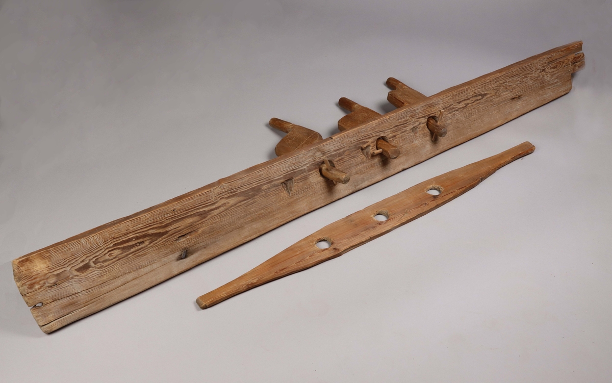 A wooden strand twister, one part of a rope twister maschine made for twisting three strands into a rope.  It consists of five parts, one tall board with drilled holes, three wooden turning wings and one shorter board with handles at each end. The two boards have drilled holes that keeps the wooden wings attached to the boards