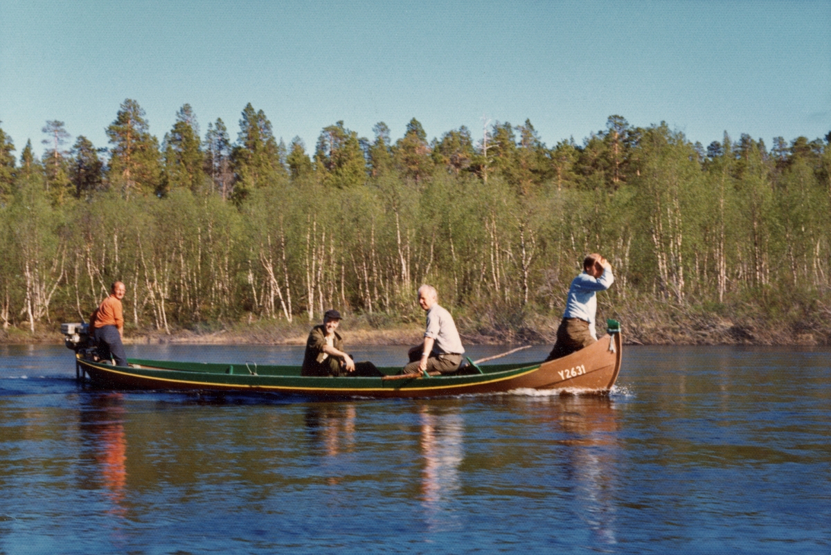 Styret for Direktoratet for statens skoger på befaring i elvebåt på Anarjokka.  Stilleflytende elv med bjørkebelte langs bredden, furuskog lengre inne på land.  Båtføreren er uidentifisert, de andre er fra venstre: direktør Thorstein Sjursen, styremedlem Arne Kaare Løfsgaard, skoginspektør Egil Olav Skoglund. Finnmarksvidda.