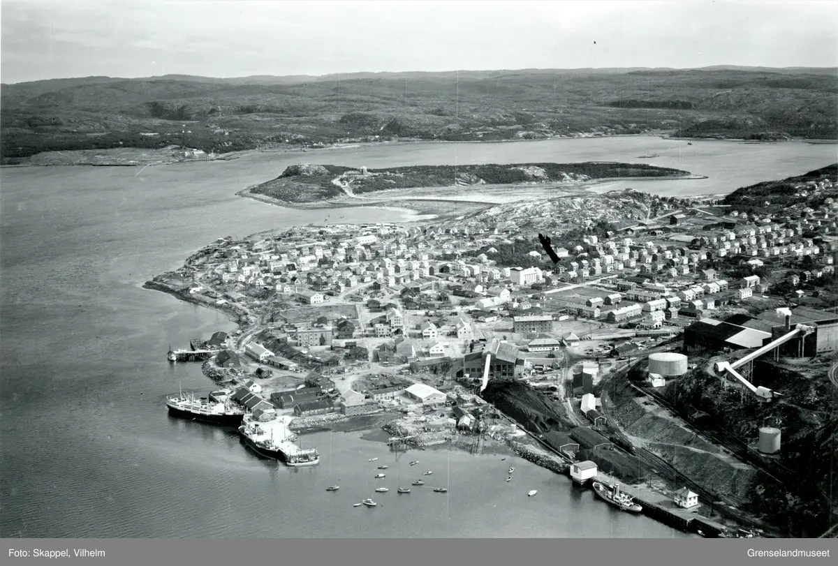 Flyfoto av Kirkenes med Jakobsnes og Ytre Lid i bakgrunnen. Sabelskjær til venstre i bildet. Prestøya fra midten og mot høyre i bildet. Kulturhuset Malmklang. Deler av AS Sydvaranger i høyre front av bildet.