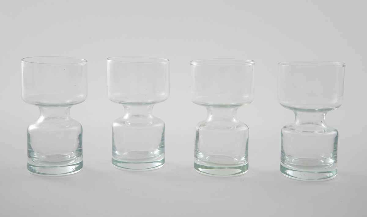 Elleve lysestaker i glass utformet som en sylinder som snevres inn på midten. Den øverste delen er litt videre enn den nederste. 

Fire lysestaker er i klart glass.
Sju lysestaker er i røykfarget, halvgjennomsiktig glass.