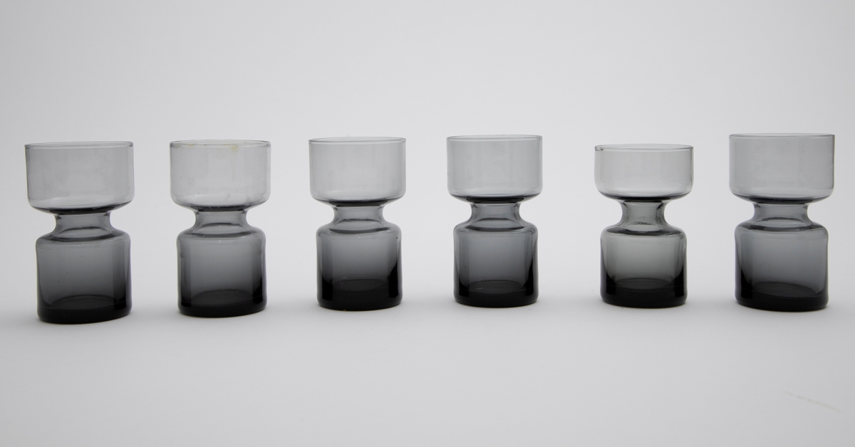 Elleve lysestaker i glass utformet som en sylinder som snevres inn på midten. Den øverste delen er litt videre enn den nederste. 

Fire lysestaker er i klart glass.
Sju lysestaker er i røykfarget, halvgjennomsiktig glass.