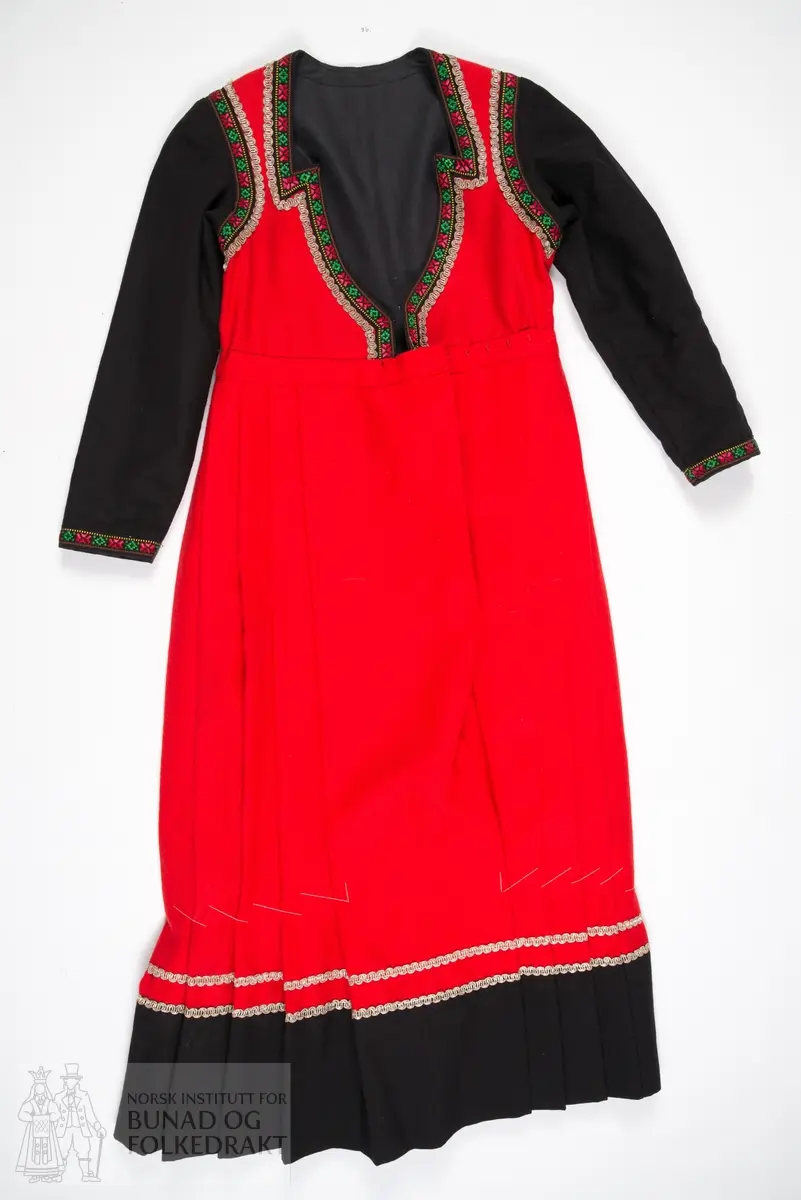 Kjole.
Trøye sydd til stakk. Trøya har røde forstykker, det er ikke en hel trøye som har fått røde fremstykker/bringesylv sydd på utenpå. 
Det svarte stoffet er et tynt ullstoff, det røde er litt kraftigere, begge er i lerretsbinding.
Foret med svart bomullslerret. Kanta med svarte bomullsbånd med blomstermønster, samt sølvfargede metallbånd.
Lukkes midt foran med hekter. 
Stakken er av rød ull, samme type som i livet. Lagt i legg til linningen med et flatt parti foran. 
Splitt midt foran, linningen lukkes med hekter. Stakken er uforet. Kanta nederst med en bred bord av samme svarte ullstoff som i trøya, stakkekanten er i tillegg dekorert med to rader sølvfargede metallbånd, samme type som på trøya. 
Både håndsøm og maskinsøm.