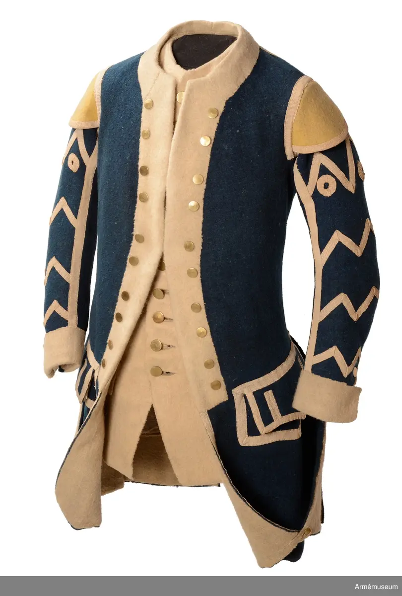 Rock av blått kläde med vita ärmuppslag och bröstrevärer av vitt kläde, gula axelkarmar, dekorationer av vävda vita band i tre olika bredder och släta mässingsknappar. Rocken är lång, med svängd mitt-fram-linje. Troligen nådde den nästan till knät på den som bar den. Den har 20 parvis ställda knappar fram, men knäpps kant i kant med två hyskor och hakar.
Den är konstruerad med hela framstycken som går runt till baksidan och bildar sidstycken. Delat bakstycke med mitt-bak-söm, samt tvåsömsärm. Sidsömmarna, ärmsömmarna och mitt-bak-sömmen är dekorerade med band. Två lågt ställda horisontella fickor fram med bandprydda ficklock, falska knapphål och två knappar vardera.
Skört med uppvik nertill fram. Sicksackdekorationer och rundlar på ärmarna.
Foder av vit boj i bålen, men oblekt bomull i ärmarna.