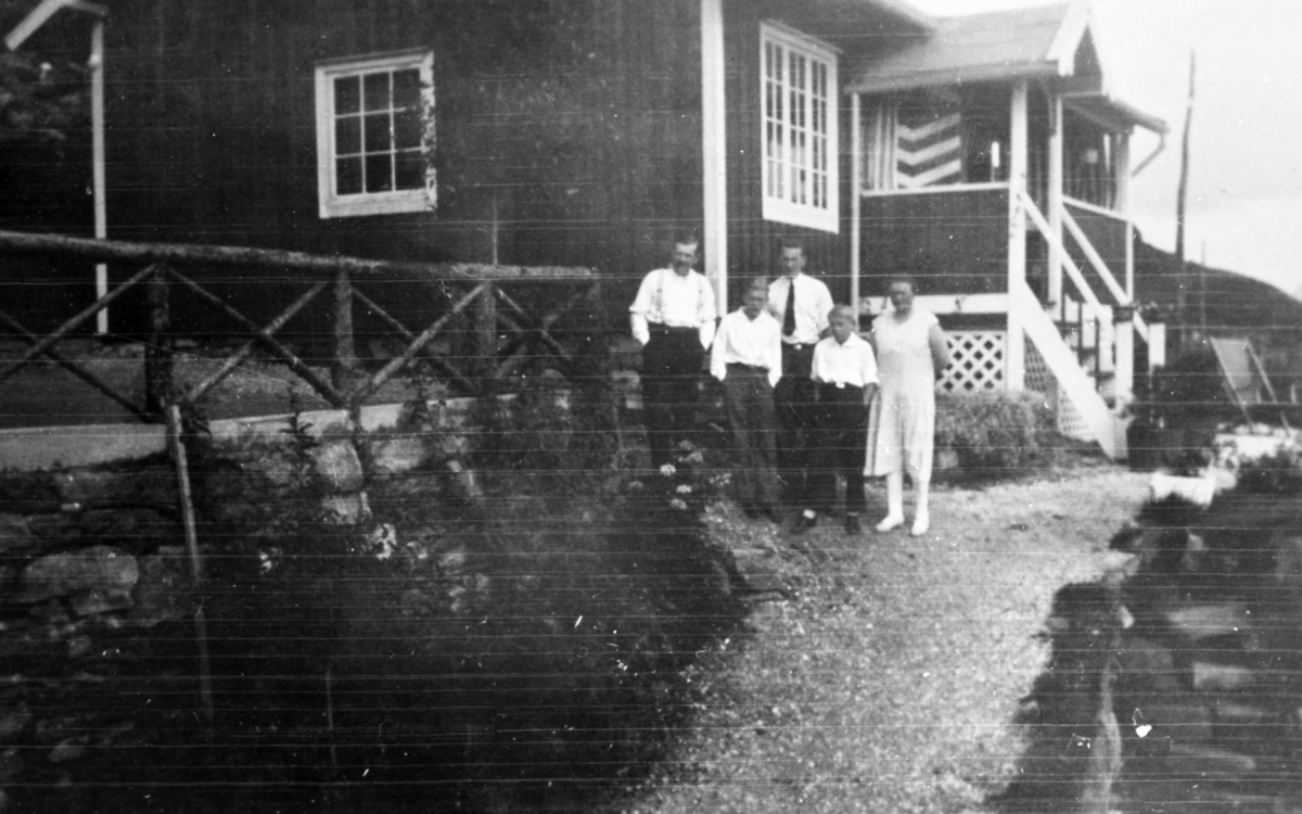 Gruppeportrett av en familie i hagen foran et hus.