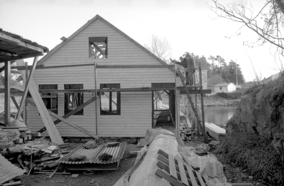 Dokumentasjonsbilder i serie fra gjenoppføringa av Larsnesbua, også kallt Seljeset-buda på Sunnmøre Museum, februar 1992. Einar Fagerli er arbeidsleiar for arbeidet, og det er gjennom "Arbeid for trygd"- ordninga ein har fått folk til arbeidet.
