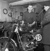 Två män står och pratar vid en Husqvarna motorcykel. År 1956.