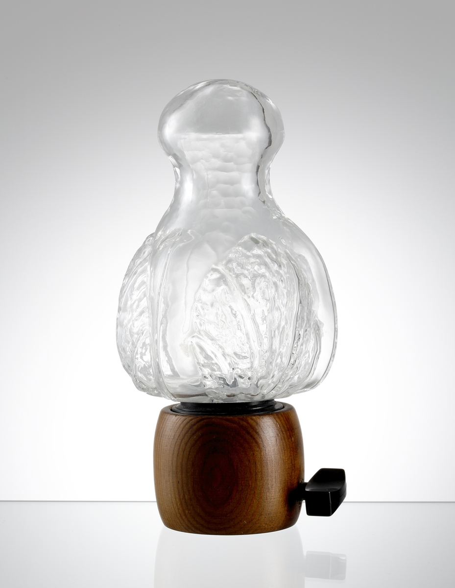 "Eden", formgiven av Lars Hellsten. Klotformad övre del med mjukt insvängd hals och rund kropp. Bladdekor i relief. Kvarndel i trä och plast.