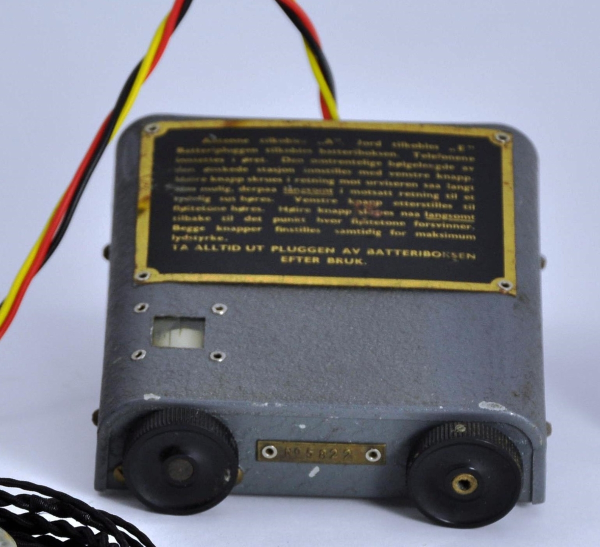 Liten radio i grå metall, rektangulær i formen. På den ene kortsiden er det to knapper til å stille inn bølgelengde og volum med. På "baksiden" er det festet en ledningen med batteriplugg, som skal festes til en batteriboks. Her er det også uttak til antenne, jording og øretelefoner. På toppen av boksen er det festet en bruksanvisning i metall. Mellom knappene på den ene kortsiden er produksjonsnummeret festet; No.5822.