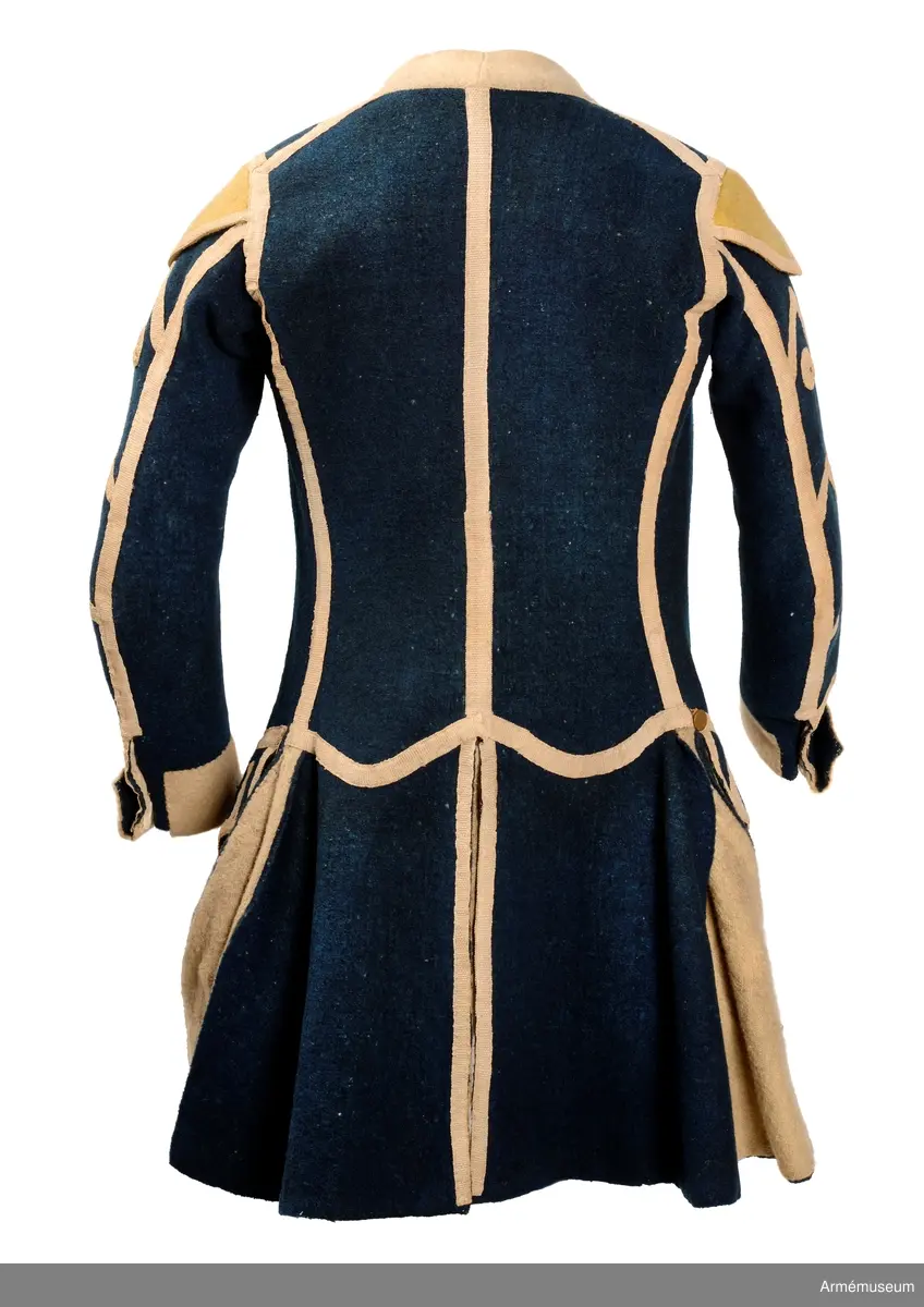 Rock av blått kläde med vita ärmuppslag och bröstrevärer av vitt kläde, gula axelkarmar, dekorationer av vävda vita band i tre olika bredder och släta mässingsknappar. Rocken är lång, med svängd mitt-fram-linje. Troligen nådde den nästan till knät på den som bar den. Den har 20 parvis ställda knappar fram, men knäpps kant i kant med två hyskor och hakar.
Den är konstruerad med hela framstycken som går runt till baksidan och bildar sidstycken. Delat bakstycke med mitt-bak-söm, samt tvåsömsärm. Sidsömmarna, ärmsömmarna och mitt-bak-sömmen är dekorerade med band. Två lågt ställda horisontella fickor fram med bandprydda ficklock, falska knapphål och två knappar vardera.
Skört med uppvik nertill fram. Sicksackdekorationer och rundlar på ärmarna.
Foder av vit boj i bålen, men oblekt bomull i ärmarna.