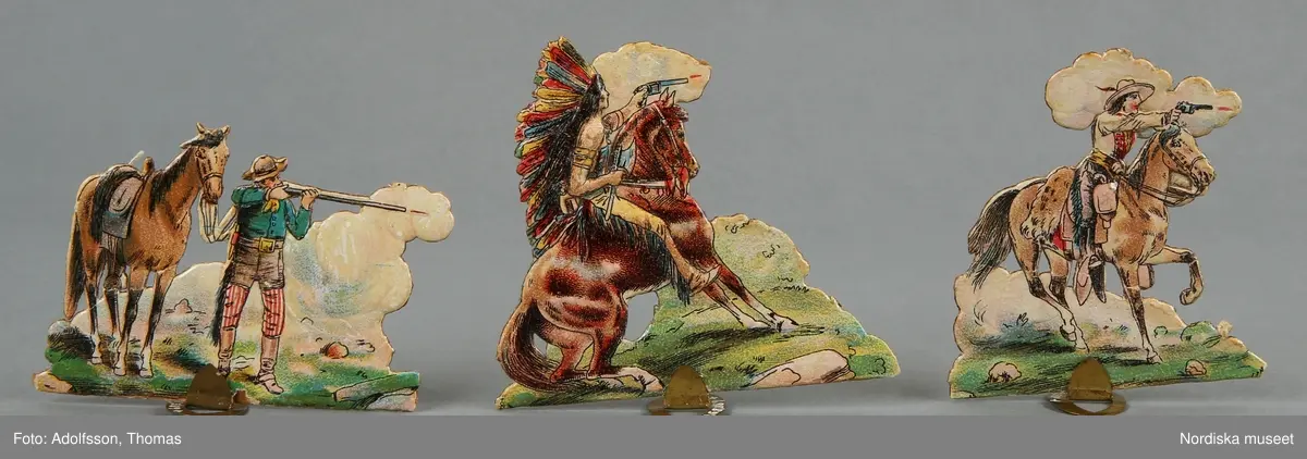 Pappersleksak i flera delar (18 lösa bitar enligt katalogkort) föreställande kamp mellan indianer och cowboys i vilda västern.