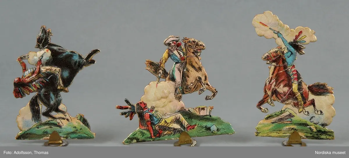 Pappersleksak i flera delar (18 lösa bitar enligt katalogkort) föreställande kamp mellan indianer och cowboys i vilda västern.