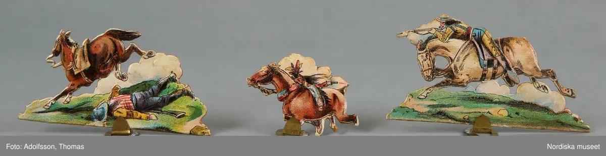 Pappersleksak i flera delar (18 lösa bitar enligt katalogkort) föreställande kamp mellan indianer och cowboys i vilda västern.