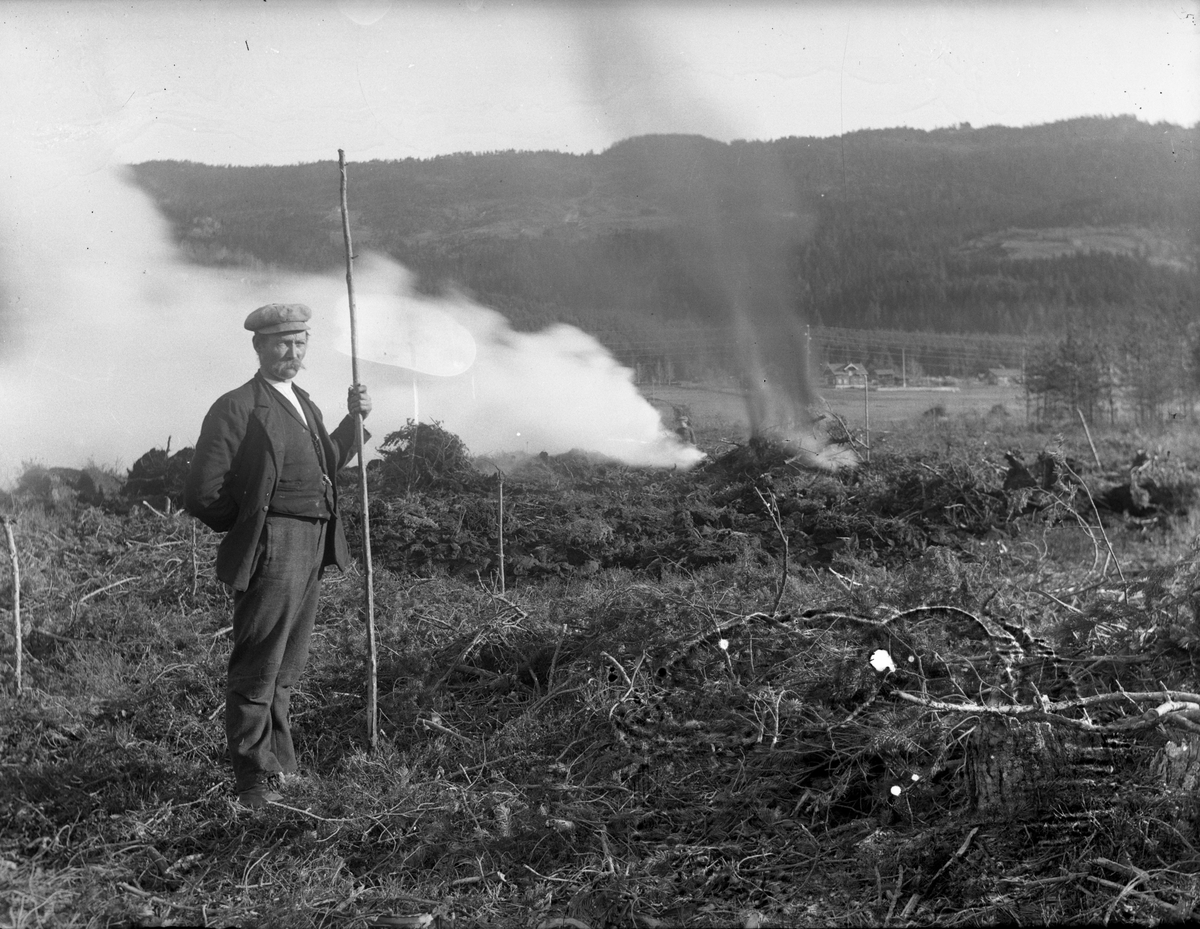 Fotosamling etter Kjetil Skomdal (1881-1971). Fotografen virket i perioden 1910 til 1960 og hadde eget mørkerom hvor han også tok imot film fra andre fotografer. I perioden var han også postbud i Fyresdal. Portrett av mann som arbeider med avbrenning av hogstflate.