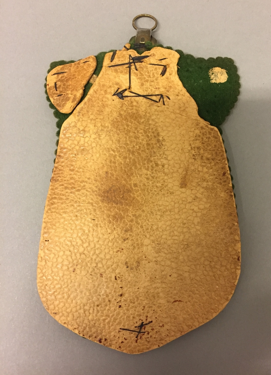 Lomme i grøn filt, med kartong bakside. Brodert og dekorert med ei stjerne i metall. Oppheng.