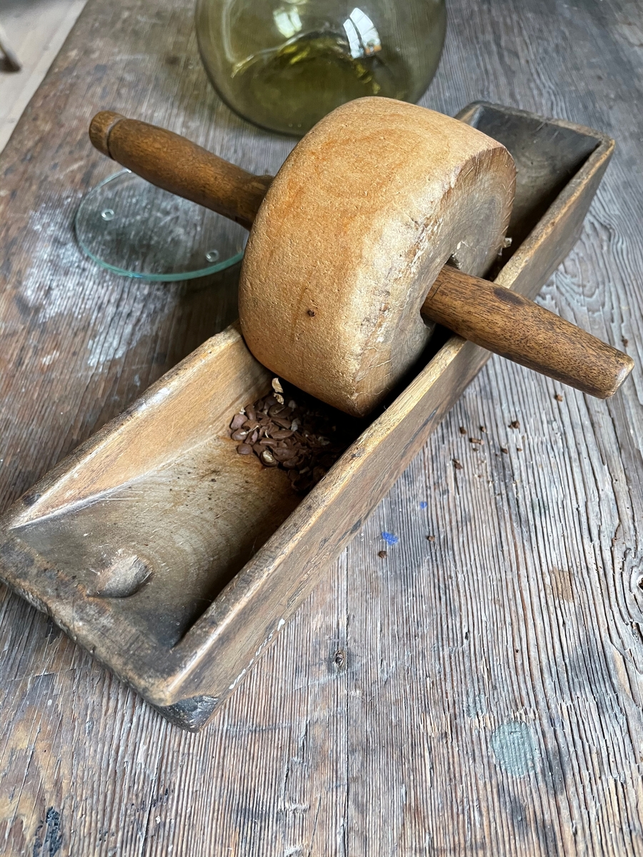 En rektangulär utskuren skål med en cirkelrund trissa med ett handtag rakt igenom.
