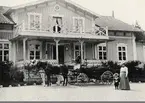 Ett ekipage har kört fram framför huvudbyggnaden på Skirsnäs, en sommardag ca 1900. 
Till höger syns en kvinnlig medlem ur (trol.) familjen Sylvan med en liten pojke.