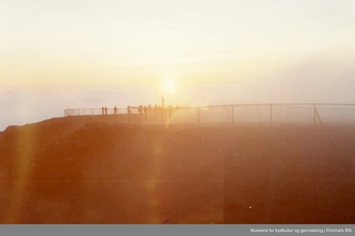 Nordkapp. Midnattsol. Turister på platået, i midten er Oscarstøtten synlig. Sommeren 1972.