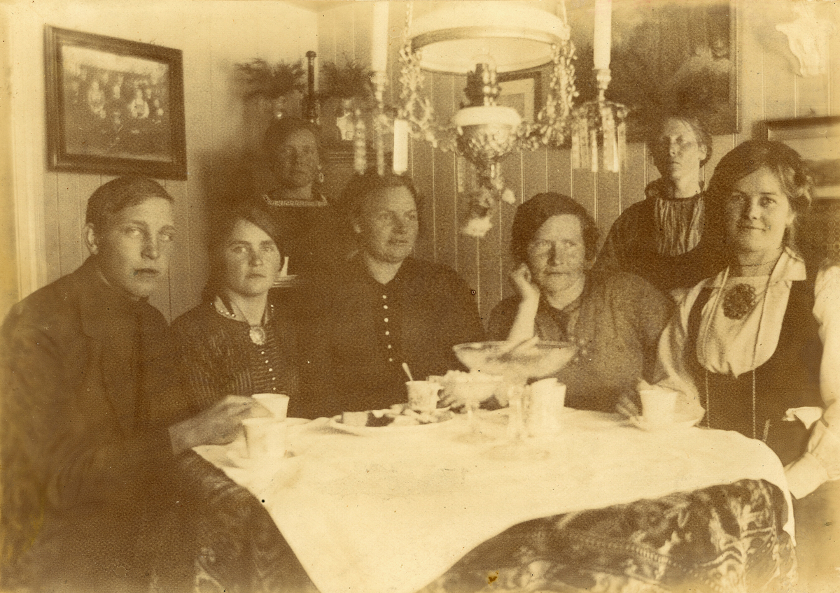 Kaffeselskap i oppstugo i Krossvegen.  F.v Johannes Saga f. 1897 d. 1981, Anne H. Saga f. 1894, Ronnaug H. Saga f. 1888 d. 1976, Dordi E. Nordbø f. 1882 d. 1966, Mari Saga f. 1882 d. 1973, Ingeborg Skogen f. 1872 d. 1958 og Bergit E. Nordbø (Bia) f. 1890 d. 1936.