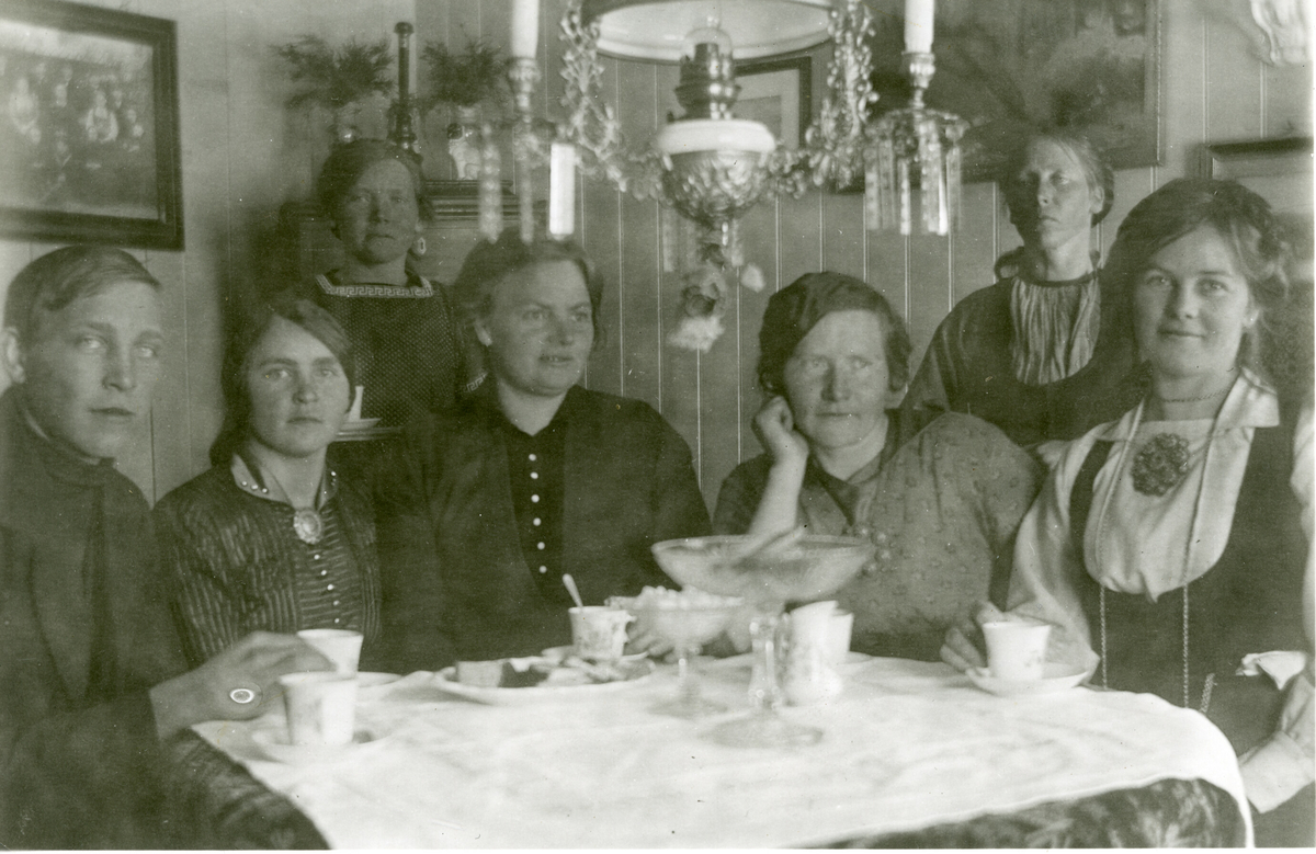 Kaffeselskap i oppstugo i Krossvegen.  F.v Johannes Saga f. 1897 d. 1981, Anne H. Saga f. 1894, Ronnaug H. Saga f. 1888 d. 1976, Dordi E. Nordbø f. 1882 d. 1966, Mari Saga f. 1882 d. 1973, Ingeborg Skogen f. 1872 d. 1958 og Bergit E. Nordbø (Bia) f. 1890 d. 1936.
