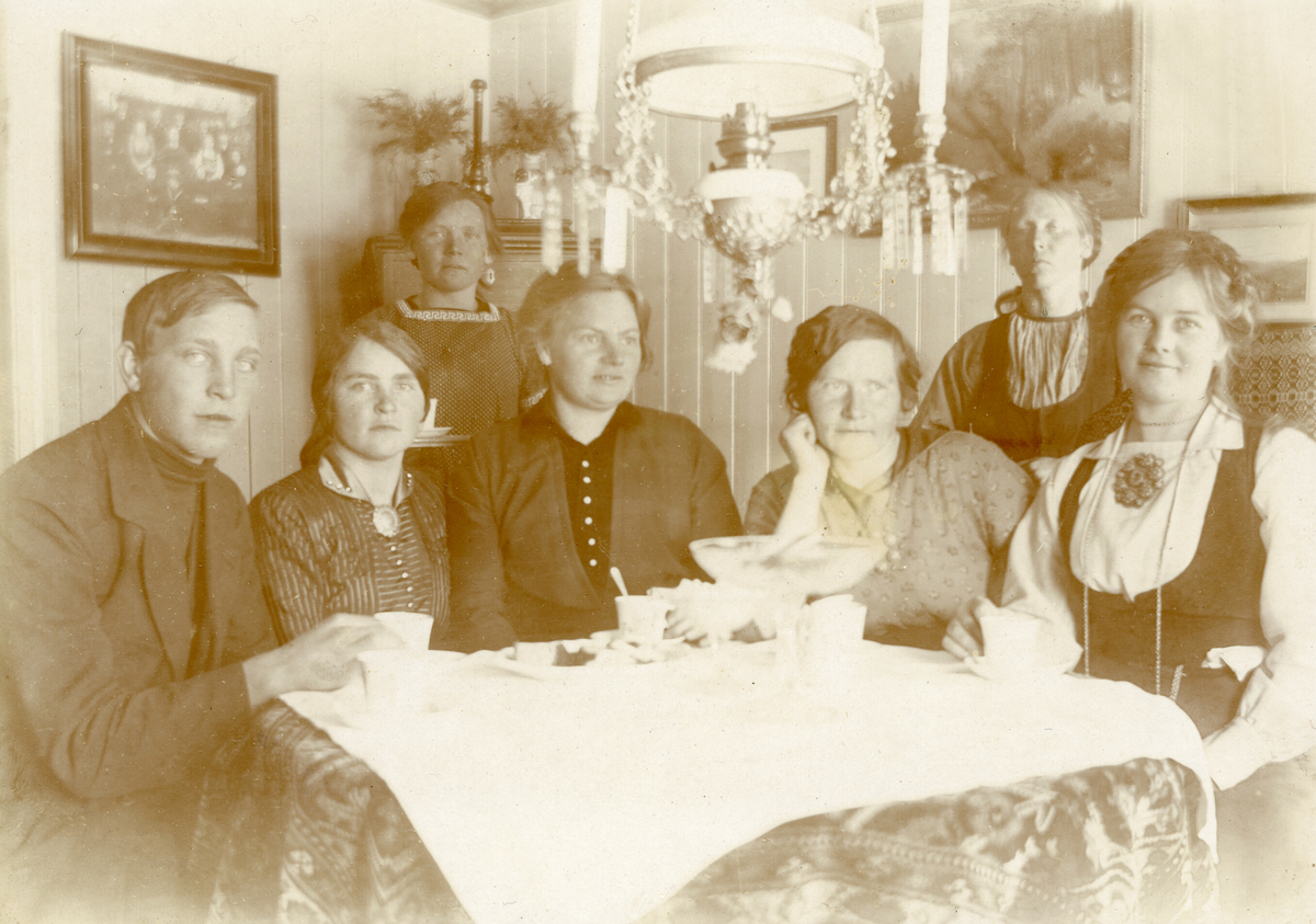 Kaffeselskap i oppstugo i Krossvegen.  F.v Johannes Saga f. 1897 d. 1981, Anne H. Saga f. 1894, Ronnaug H. Saga f. 1888 d. 1976, Dordi E. Nordbø f. 1882 d. 1966, Mari Saga f. 1882 d. 1973, Ingeborg Skogen f. 1872 d. 1958 og Bergit E. Nordbø (Bia) f. 1890 d. 1936.