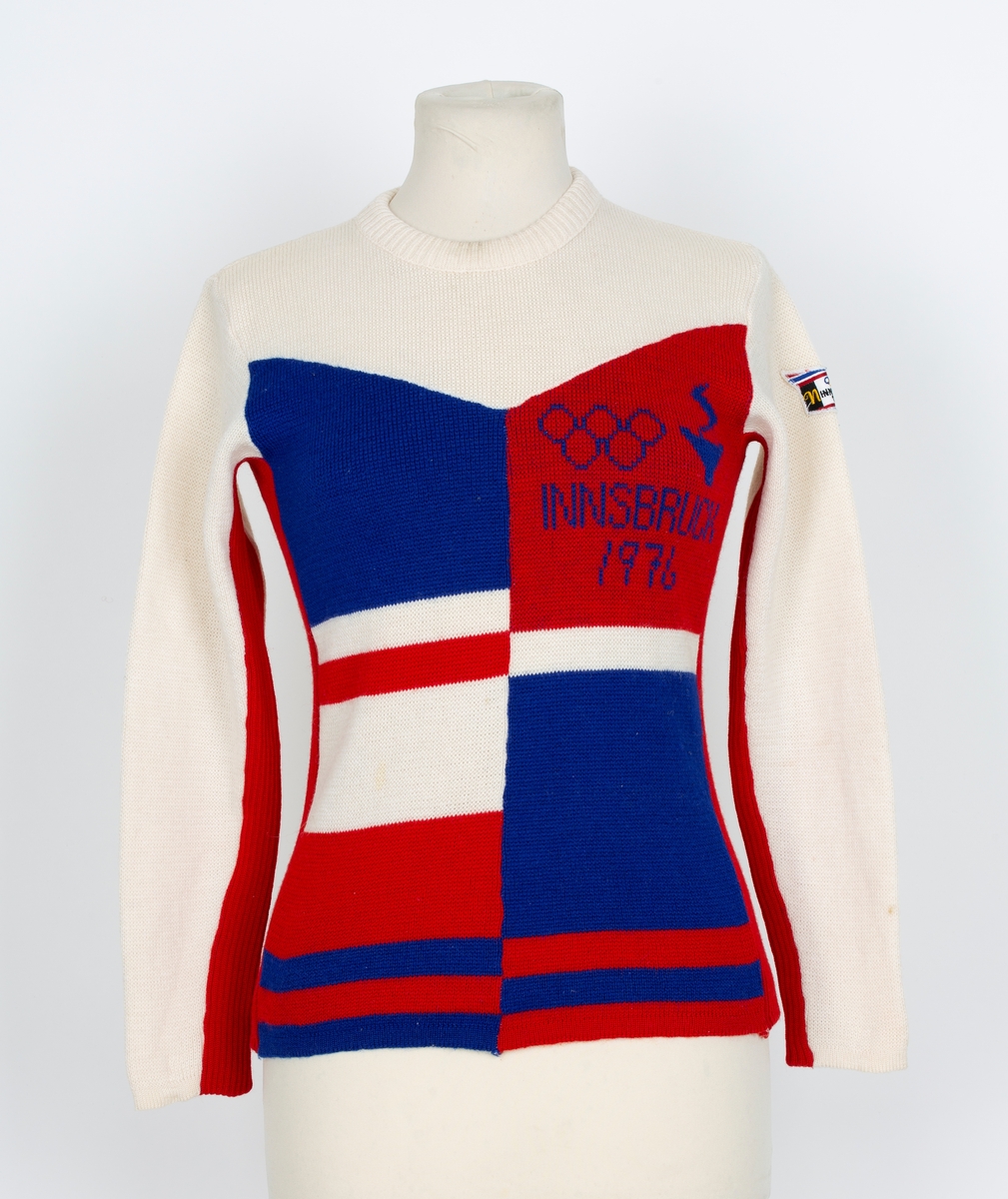Genser. OL genser fra Insbruck 1976. Lange ermer. Rund hals. Hvit, rød og blå i felter og stripet.
Merke med 5 olympiske ringer og Insbruck 1976 påsydd ermet.