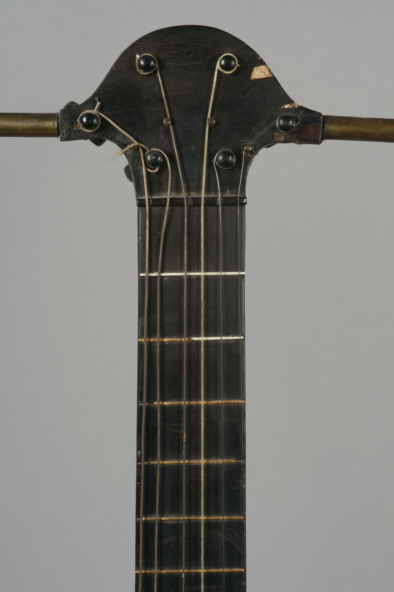 Vanlig gitar i omtrentlig gresk lyreform: korpus, gripebrett og to armer i et stykke. Armene forbundet øverst, gjennom skruekassen, ved et åk av metall. 6 strenger.

Stemmeskruer av ibenholt med perlemorsøye. Skruene festet undenifra. 13 bånd: 4 av ben, 9 av tre. 2 lydhull i form av gjennombrutte rosetter. Hals, gripebrett, strengefestet, fotstykke og kant rundt lydhullene av ibenholt. Knapper til strengefest av ibenholt med perlemor innlegg. Lokk av gran, sider og bunn mahogny. 
På innsiden av korpus to ribber av nåletre på tvers over bunn helt fram til sargene. 1 ribbe på tvers under lokk ovenfor rosettene.

Stil: Empire.