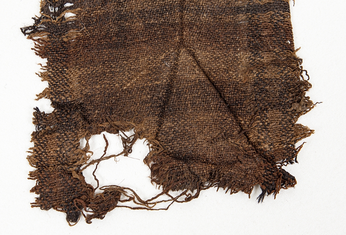 Arkeologiskt föremål. Bit av ylleväv, kypert. 