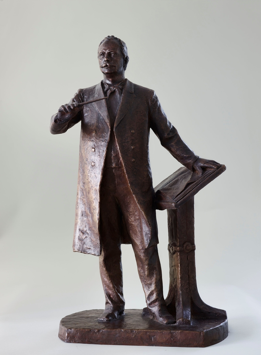 Komponist og dirigent. Støypt etter ASM 103 i gips. Truleg eit utkast til eit monument over Svendsen som ikkje vart realisert. Det finst eit monument over Svendsen, det vart avduka i 1940 framfor Oslo konserthus.