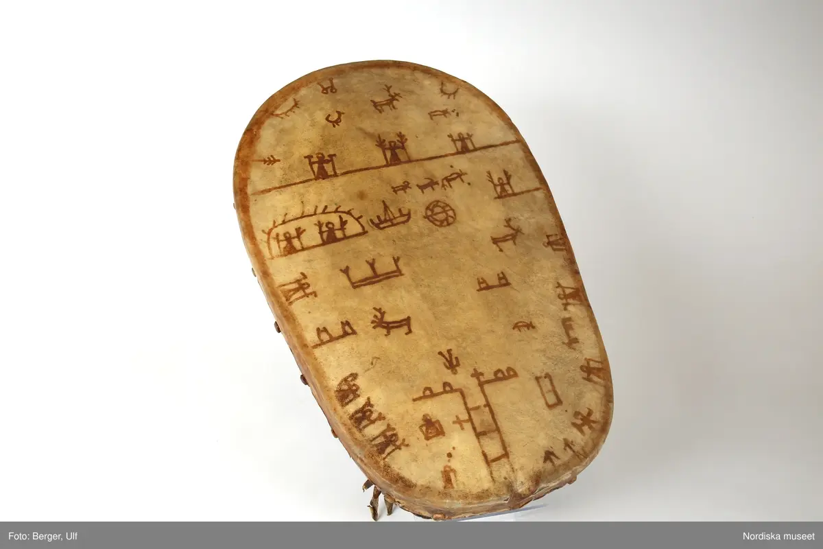 Huvudliggaren:
"Lapptrumma. Dep. 15/11 1943. Deposition av Statens Hist. Museum enl. instr. 2/2 1943. [Tidigare numrering] St. H. M. 360:2."

Utdrag från: Harrisson Lindbergh, Katarina och Harrison, Dick: Schefferus samiska trumma, i 101 föremål ur Sveriges historia, sid 204, Norstedts 2013:
"Det förhållandevis tjocka membranet av renhud är välspänt och fäst vid konstruktionen med hjälp av tränaglar. Stommen är tillverkad av vridvuxen tall. Fem hål har borrats för hängen, tre upptill och två nedtill. Av särskilt intresse är tolkningen av figurerna på trumman. Vi ser två fält - ett litet övre och ett större undre — som skiljs åt av en tvärgående linje. Tecknen är gjorda med ett trubbigt stift, kanske av trä eller ben. Färgen är med stor sannolikhet tillverkad av albark."