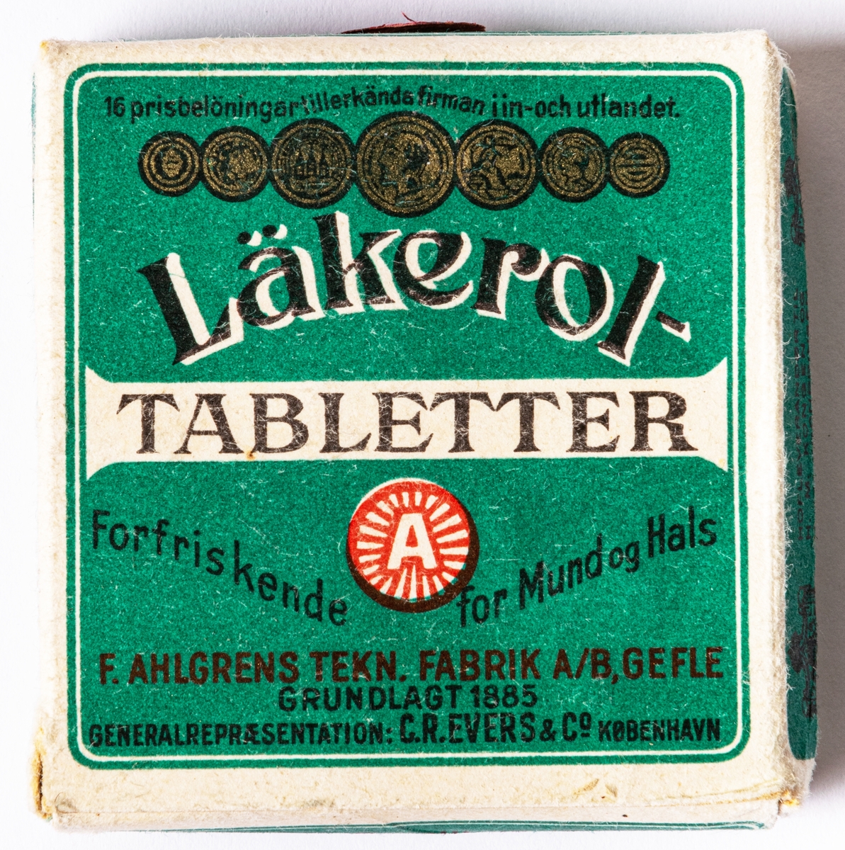 Tablettask i papper med innehåll. Läkerol-tabletter, med dansk text. Blågröna fält med vita ramar.