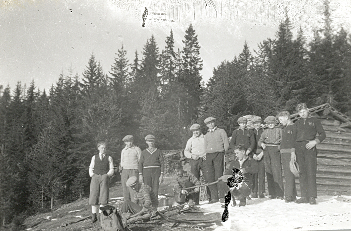 Gruppe unge menn lager kaffe på bål.  