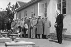 En man med hatt i händerna håller ett tal framför Vättermuseet i samband med dess invigning. Till vänster står manskören Sångarbröderna.