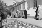 En man med hatt i händerna håller ett tal framför Vättermuseet i samband med dess invigning. Mannen är Olle Ekblom, landshövding i Jönköpings län. Till vänster står manskören Sångarbröderna.