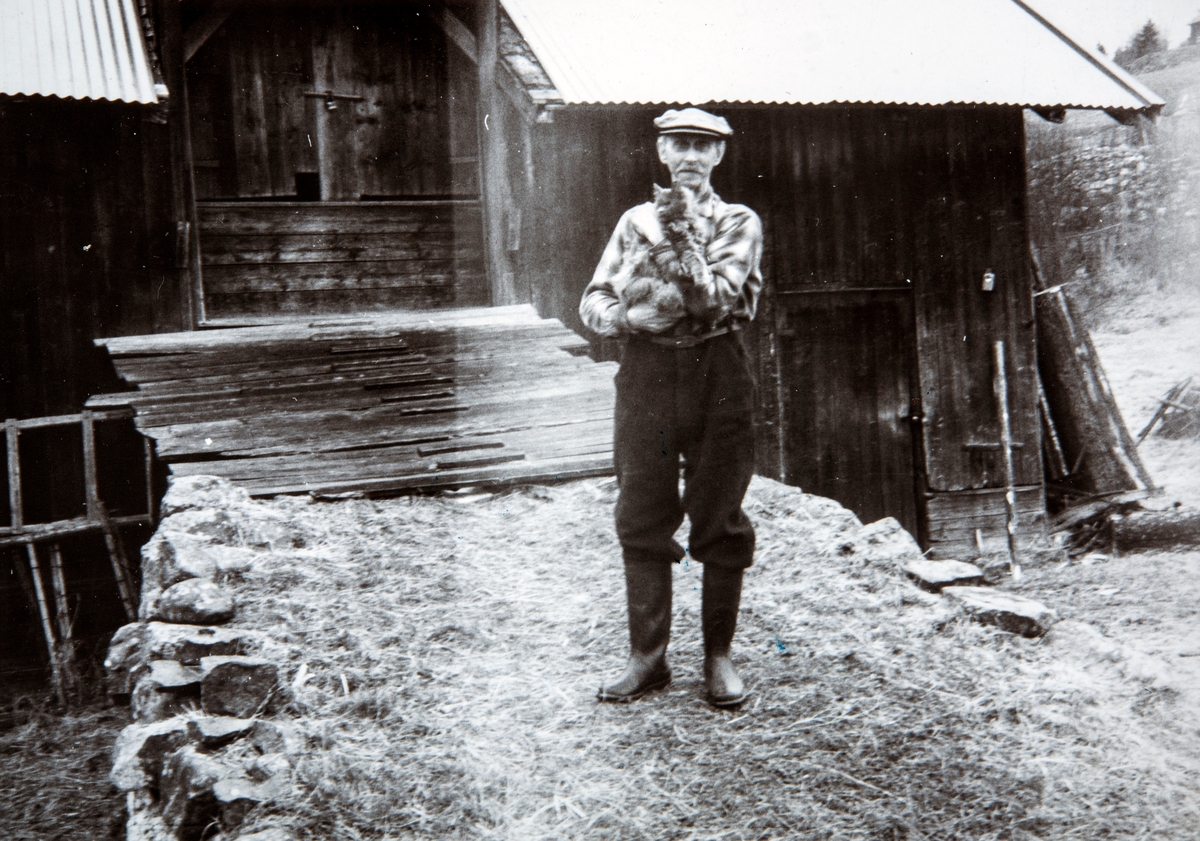 Lauritz Bånerud med katten "lita" på armen,  foran låven hjemme på Bånerud, Åsvangvegen 172 i Romedal. Bilde tatt på 1960-tallet.