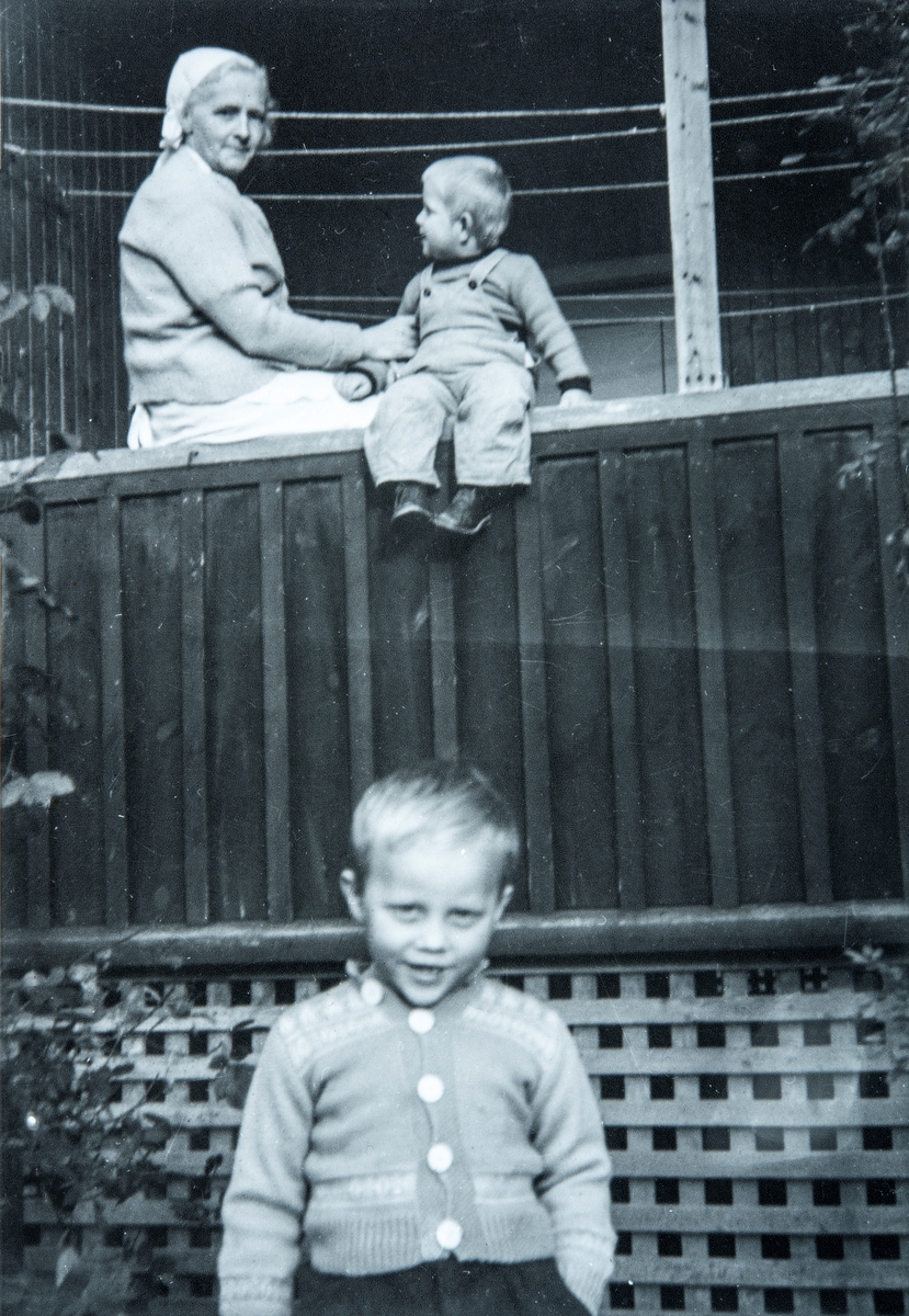 På Stange sykehus. I front, Terje Bånerud (f: 1947), Oppe på verandaen sitter broren Sverre Bånerud (1948-1993) på rekkverket mens søster Gerda Johnsen (senere gift Mikkelsen) holder et godt tak. Guttene er her ved en av "sol-altanene" til bygningen der de "kurerte" pasienter som var rammet av tuberkulose ved hjelp av solstråler mot huden.  Gerda ble til dagelig kalt for "Holmlund", som var navnet på plassen hun bodde.