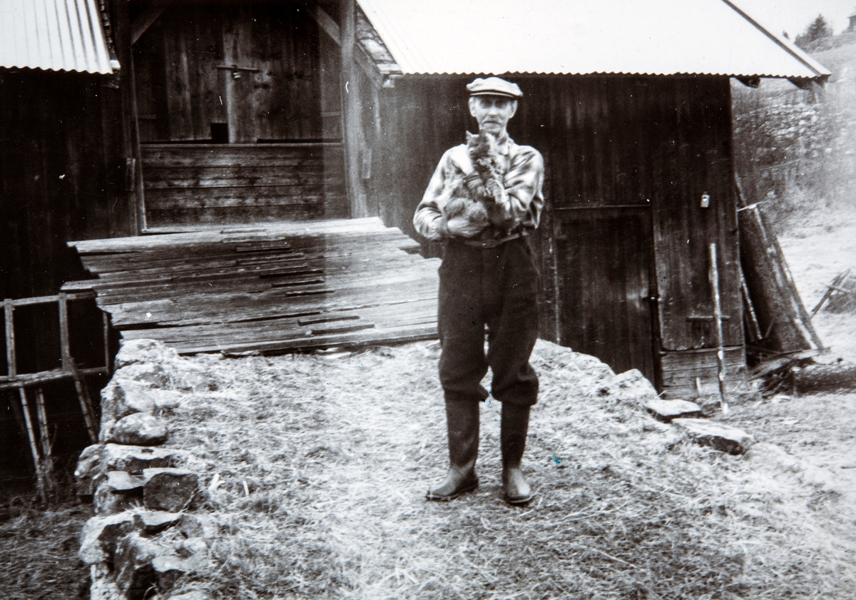 Lauritz Bånerud med katten "lita" på armen,  foran låven hjemme på Bånerud, Åsvangvegen 172 i Romedal. Bilde tatt på 1960-tallet.