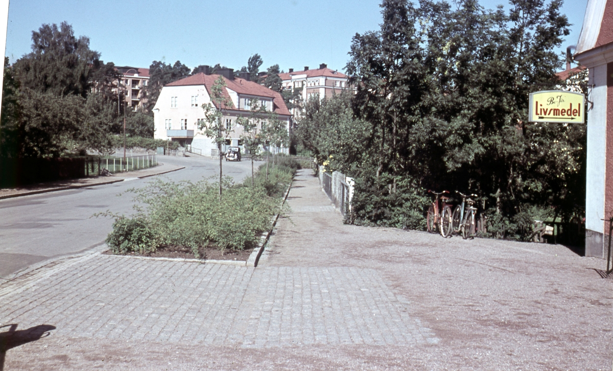 Bäckgatan ligger bredvid Universitets sjukhuset i Linköping. Sjukhuset skymtar längst bak i bilden. Det vita huset finns fortfarande kvar. Affären Be-Jis livsmedel finns inte längre och huset är numera privatbostad.  Bäckagatan tillhör stadsdelen Ramshäll och husen är från tidigt 1900-tal.