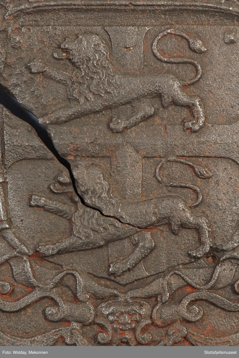 Gyldenløves våpern, omgitt av krigerske emblemer, derover på knekket bånd "ULRICH FRIDERICH"
nederst 1694