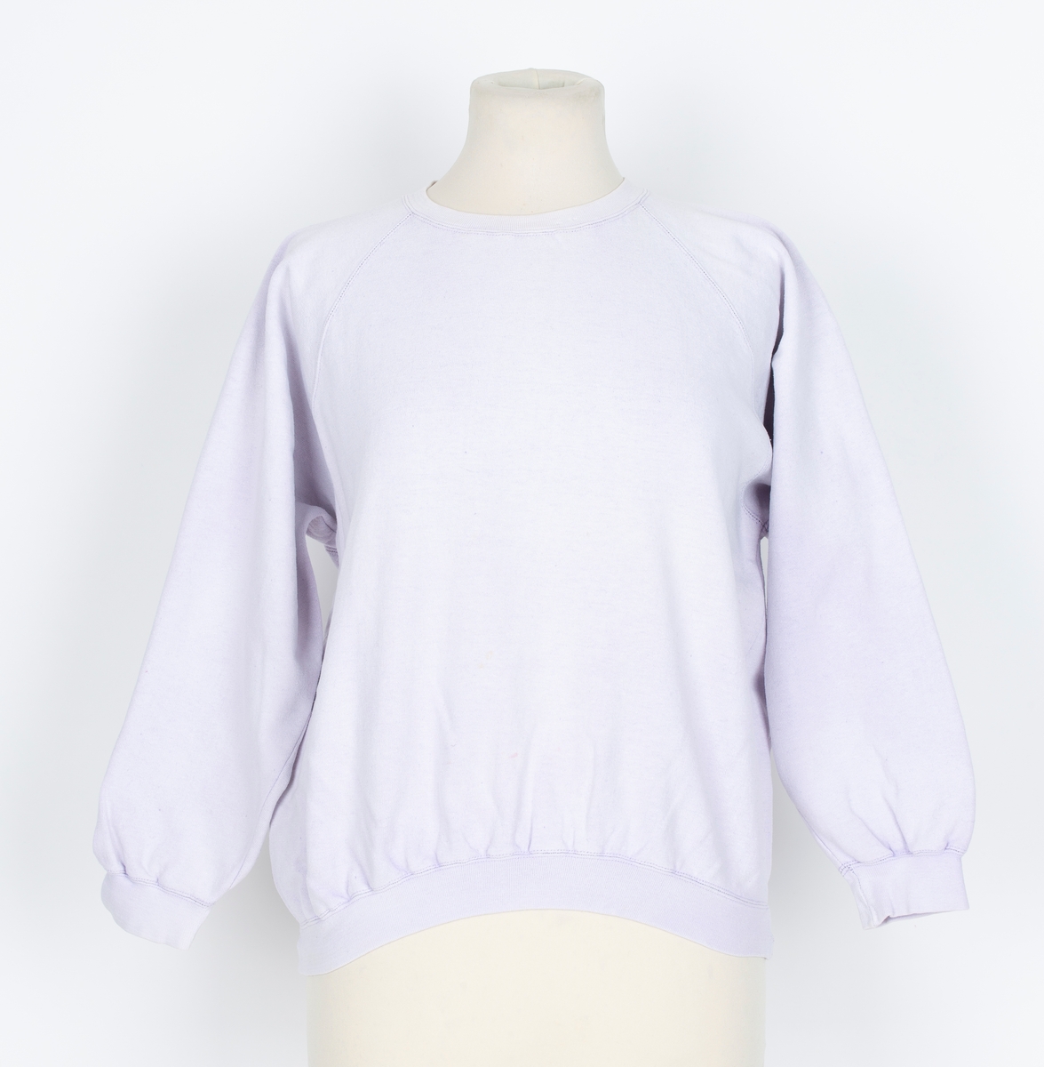 Joggedress. Todelt. Tricot. Lys lilla. Genser med raglan ermer, vrangborder. Bukse med strikk i livet, vrangbord på bukseben.
Brukt til uke-trim og fritid sent 1980-tall
