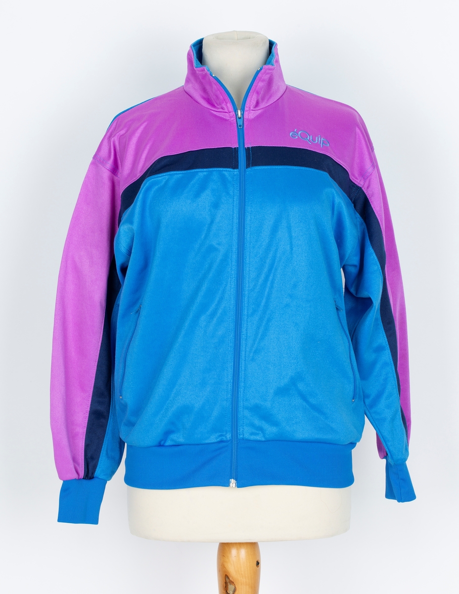 Joggedress. Lilla øverst, mørk blå stripe, blåturkis nederst.
A: jakke: Glidelås foran. Ståkrage.  
B: Bukse. Snor i livet, trikotmansjett nederst. mørk blå stripe i siden.

Kjøpt hos Wistex, Vestby.
Brukt undere sykehusopphold 1990 tallet. godt likt og mye brukt