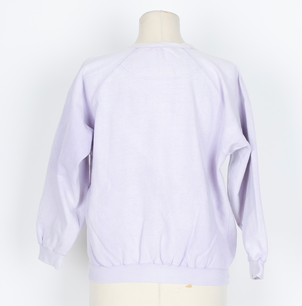 Joggedress. Todelt. Tricot. Lys lilla. Genser med raglan ermer, vrangborder. Bukse med strikk i livet, vrangbord på bukseben.
Brukt til uke-trim og fritid sent 1980-tall