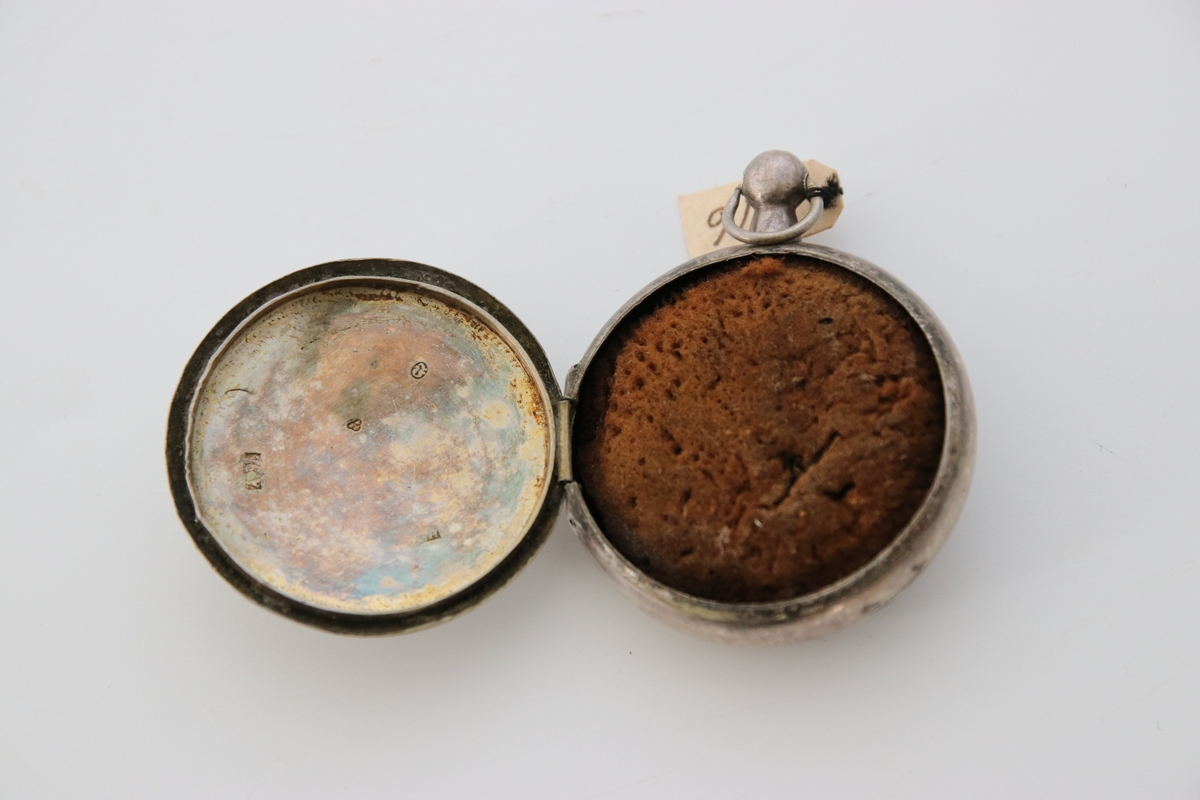 Svampdosa av silver, inuti förgylld, utan filigranslock över svampen. Båda sidorna med linjemönster.