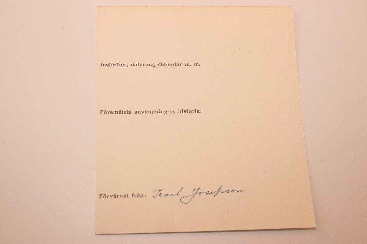 Svarvad rund ask i lackat trä. Med snidad dekor som täcker askens alla delar. Asken öppnas genom att ”delas” på mitten (består av två halvor som sammanfogas).  På askens ovansida föreställer dekoren ett fält där ändarna avslutas med bladdekor. I fältet är namnet ”Tilda” inristat. Bakom detta fält finns mer dekor föreställande blad. Dekoren på askens sidor består av lutande streck (som går i olika riktningar på de olika halvorna av asken). Asken har en rund yta med en svårtydd text i botten.
