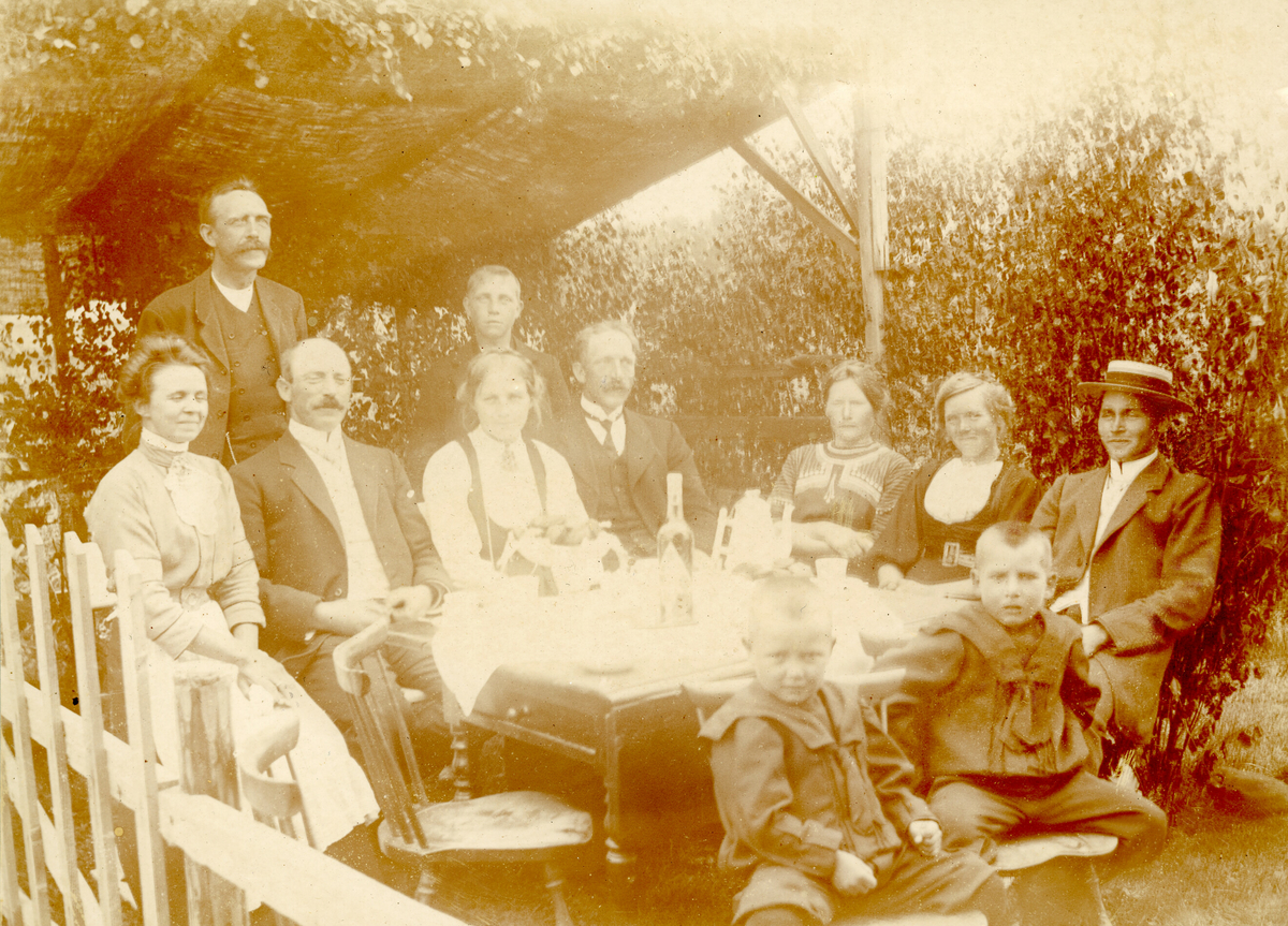 Familieselskap i lysthuset på Krossvegen i Bø.  F.v Anna Sagen, sarpsborg, Hans Sisjord ståande, Halvor H. Sagen f. 1874 d. 1955, Sarpsborg, Kari O. Saga f. 1889 d.1976, Olav H. Saga f. 1876 d. 1963, Johannes Saga ståande bak, f. 1897 d. 1981, Mari H. Saga f. 1882 d. 1973, Ronnaug Saga f. 1888 d. 1976, Kittil H. Sagen. Sitjande framme f. v Erik K. Sagen f. 1907 og Håkon K. Sagen f. 1905, begge Sarpsborg.